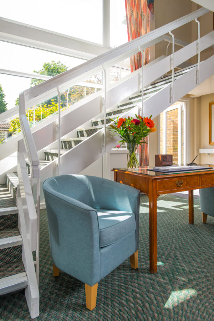 chair with welcome desk next to stairs at upper mead care home