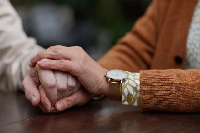 Two people holding hands in support