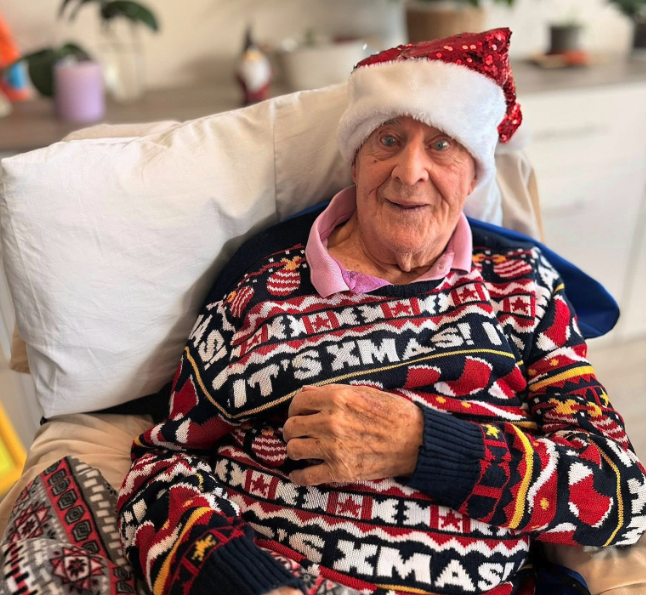resident with a penguin christmas jumping smiling in a chair